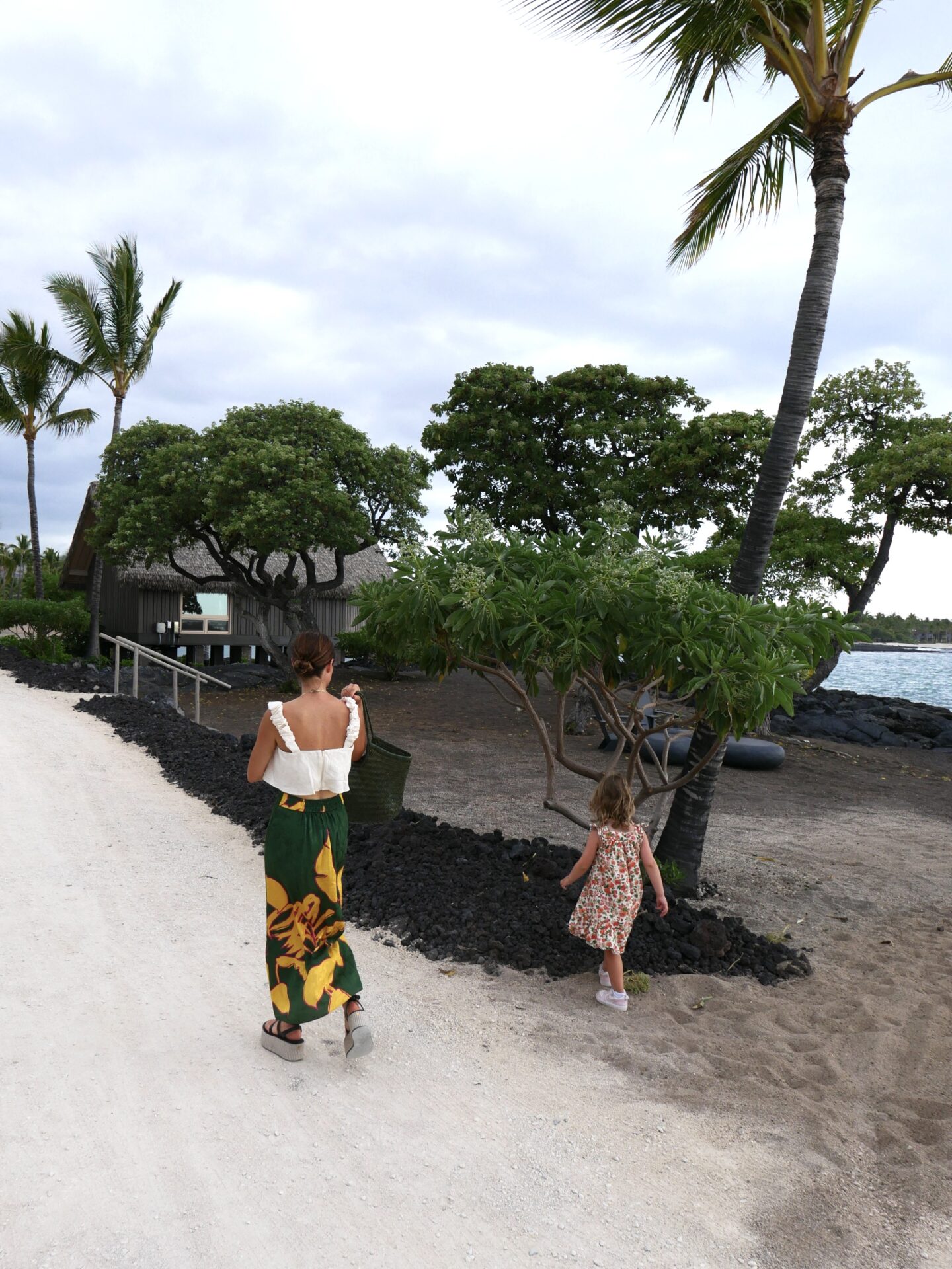 Alicia Lund with her child walking at the shore of Kona Village